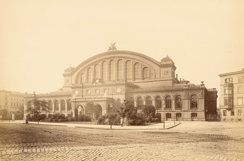 Historische Aufnahme eines Riegelbaus mit repräsentativer Fassade und hohen Rundbogenfenstern.
