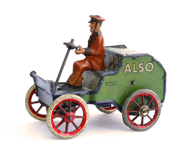 Vorwiegend grünes Blechmodell mit kleiner Karosserie, bestehend aus Sitzbereich und Motorhaube. Der Fahrer trägt einen braunen Mantel und eine Schirmmütze und hält ein Lenkrad, das schräg nach vorn montiert ist. Seitliche Aufschrift: "ALSO 700".
