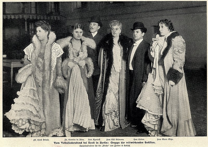 Gruppenfoto von sechs Personen: Vier Damen in langen Mänteln mit Pelzbesatz, zwei Herren in Anzug und Melone. Bildunterschrift: "Frl. Hansi Delisle, Frl. Leontine De Uhna, Herr Egenleff, Frau Lilli Lehmann, Herr Lieban, Frau Marie Götze. Vom Volksliederabend bei Kroll in Berlin: Gruppe der mitwirkenden Solisten. Spezialaufnahme für die 'Woche' von Zander & Labisch."